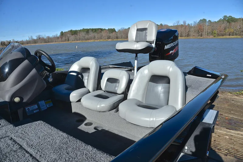 Slide: The Image of 2018 Bass Tracker Pro 19 boat with gray seating, parked by a lake. - 18