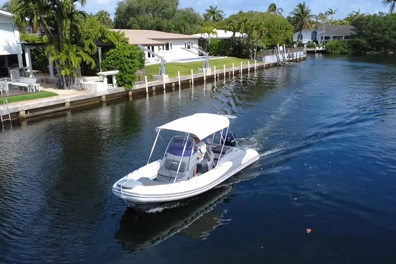 Slide: The Image of 2020 Grand Inflatables G580 boat cruising on a scenic canal with waterfront homes. - 10