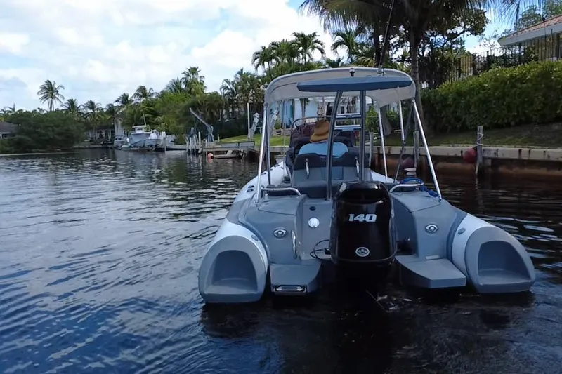 Slide: The Image of 2020 Grand Inflatables G580 boat cruising on a scenic waterway with palm trees. - 16