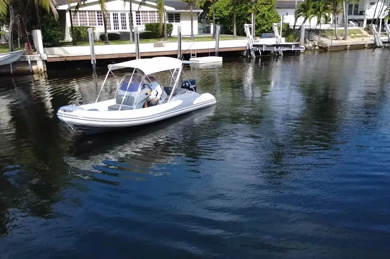 Slide: The Image of 2020 Grand Inflatables G580 boat on calm water near residential docks. - 4