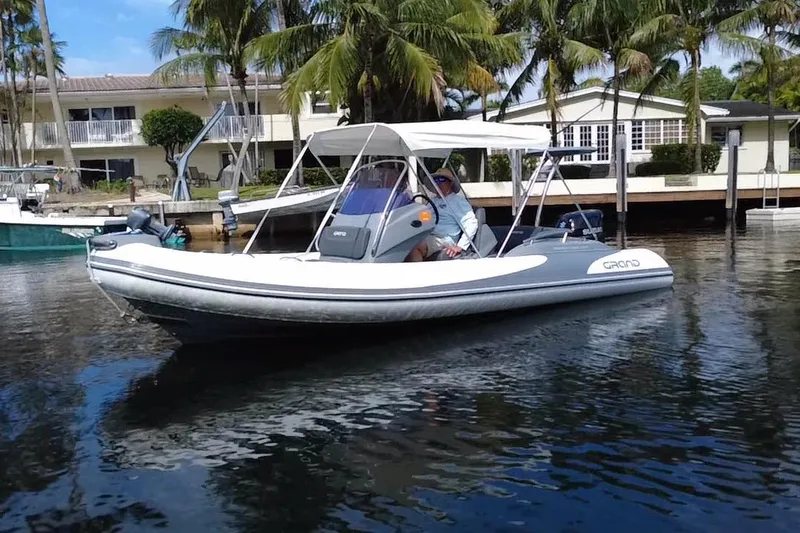 Slide: The Image of 2020 Grand Inflatables G580 boat on calm water near palm trees and waterfront homes. - 5