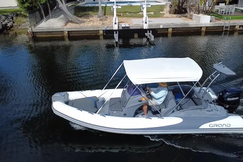 Slide: The Image of 2020 Grand Inflatables G580 boat cruising on a calm waterway with canopy and Suzuki engine. - 7