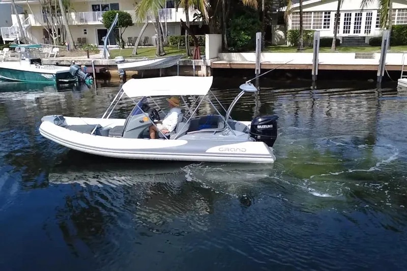 Slide: The Image of 2020 Grand Inflatables G580 boat cruising on a calm waterway near waterfront homes. - 8