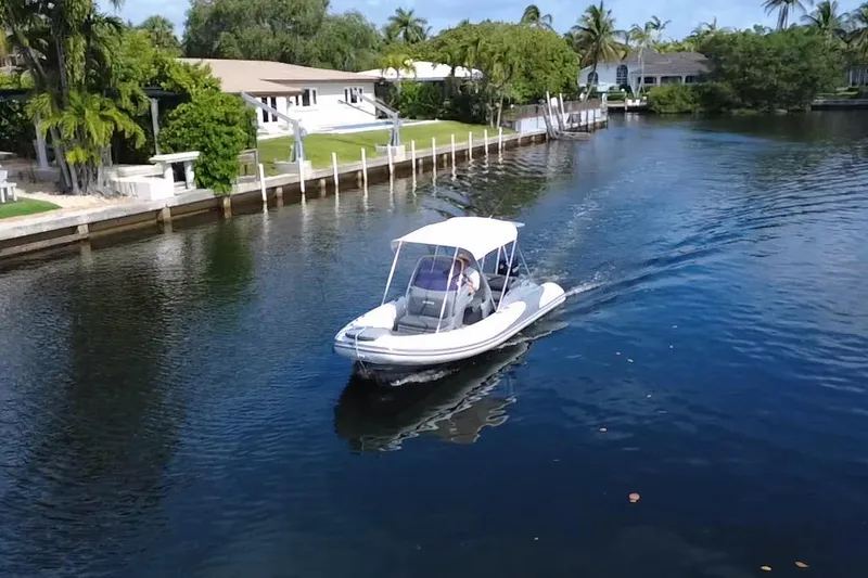 Slide: The Image of 2020 Grand Inflatables G580 boat cruising on a scenic canal with lush greenery. - 9