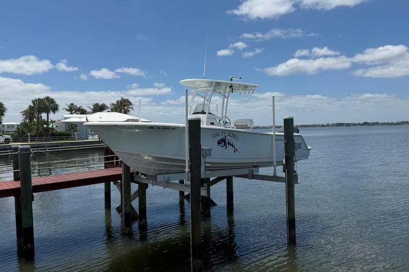 Slide: The Image of 2015 Sportsman Heritage 231 Center Console boat on lift by waterfront dock. - 2