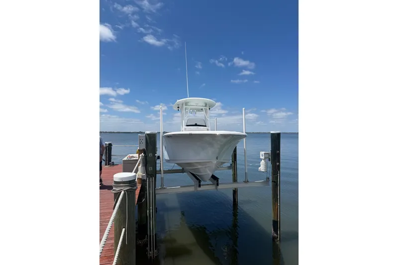 Slide: The Image of 2015 Sportsman Heritage 231 Center Console boat on lift at dock, under clear blue sky. - 3