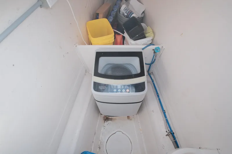 Slide: The Image of Compact laundry area on Leopard 46 yacht, featuring a washing machine and storage items. - 25