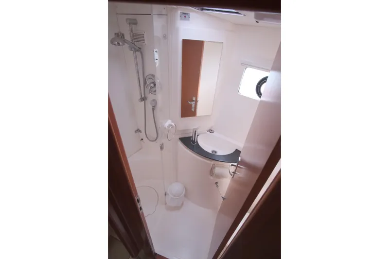 Slide: The Image of Compact bathroom in a 2007 Leopard 46 yacht, featuring shower, sink, and porthole window. - 63