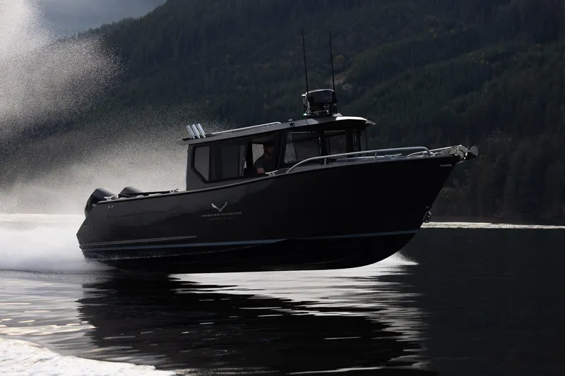 The Image of 2026 Jasper Marine Defender 22 speeding on a lake with forested hills in the background. - 1