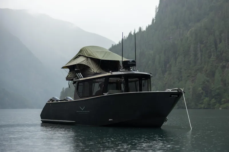 Slide: The Image of 2026 Jasper Marine Defender 22 boat anchored on a serene lake with forested mountains. - 6