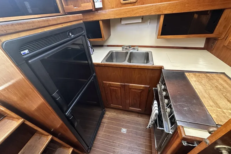 Slide: The Image of Compact kitchen in a 1987 Californian 34 boat with wood cabinetry and modern appliances. - 7