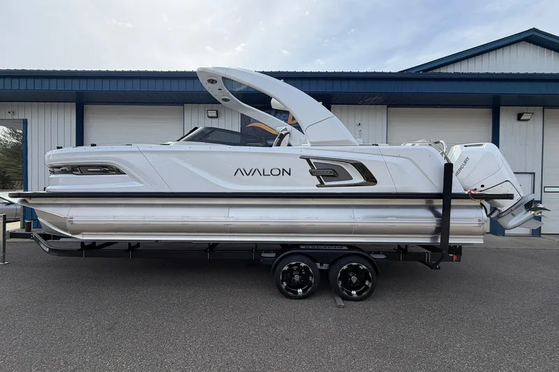 The Image of 2026 Avalon Excalibur Quad Lounge Windshield boat on trailer, sleek design, parked outdoors. - 0