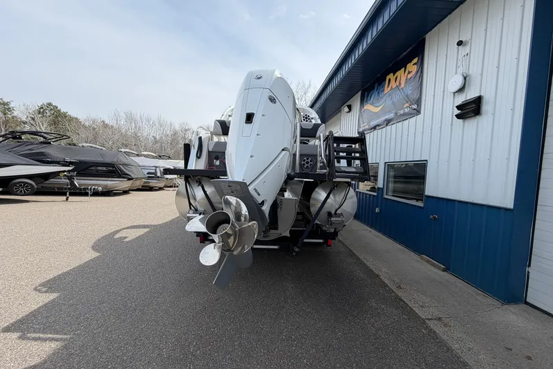 Slide: The Image of 2026 Avalon Excalibur Quad Lounge boat at marina, rear view with outboard motor. - 2