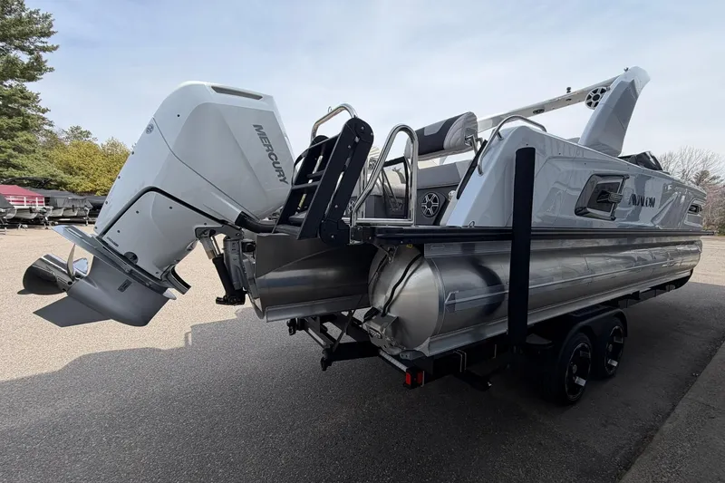 Slide: The Image of 2026 Avalon Excalibur Quad Lounge Windshield boat with Mercury outboard engine, parked outdoors. - 3