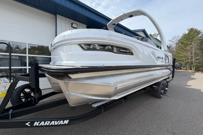 Slide: The Image of 2026 Avalon Excalibur Quad Lounge Windshield boat on Karavan trailer, parked outdoors. - 6