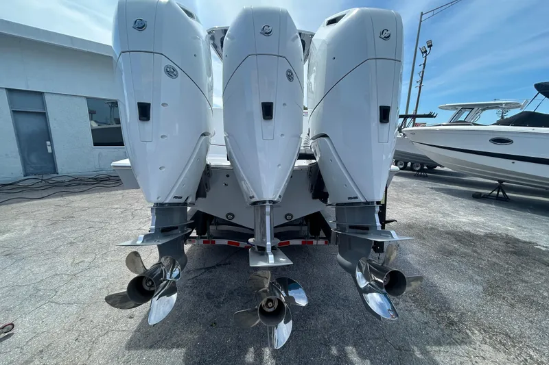 Slide: The Image of Triple outboard engines on a 2026 Contender 39 ST boat, parked on a concrete surface. - 9