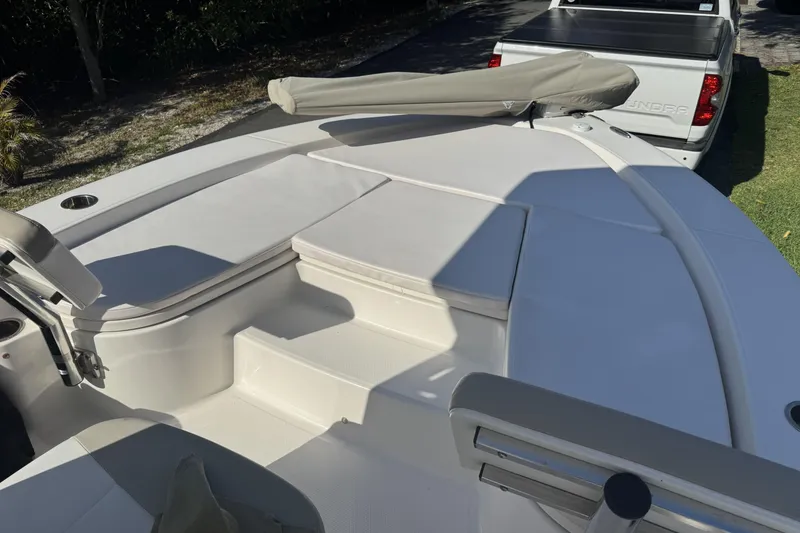 Slide: The Image of 2018 Robalo 226 Cayman boat interior with cushioned seating and steps, parked near a truck. - 12