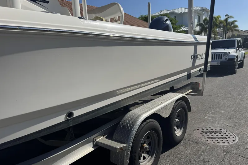Slide: The Image of 2018 Robalo 226 Cayman boat on trailer, parked on street near white vehicle. - 15