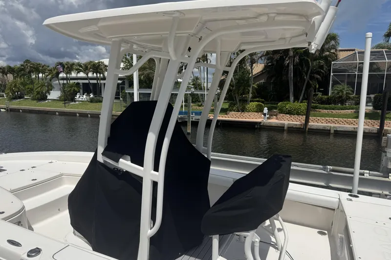 Slide: The Image of 2018 Robalo 226 Cayman boat with covered seats, docked by a canal. - 2