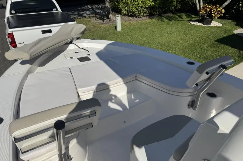 Slide: The Image of 2018 Robalo 226 Cayman boat interior with cushioned seating and a white pickup truck nearby. - 6