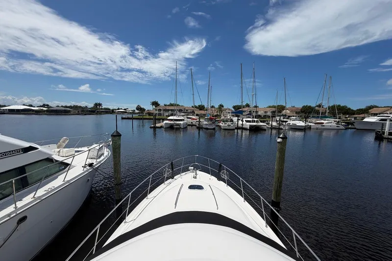 Slide: The Image of 2006 Sea Ray 44 Sedan Bridge yacht docked in a marina under a clear blue sky. - 10