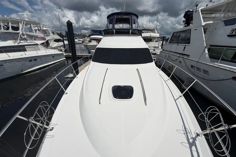 Slide: The Image of 2006 Sea Ray 44 Sedan Bridge yacht docked among other boats under cloudy skies. - 13