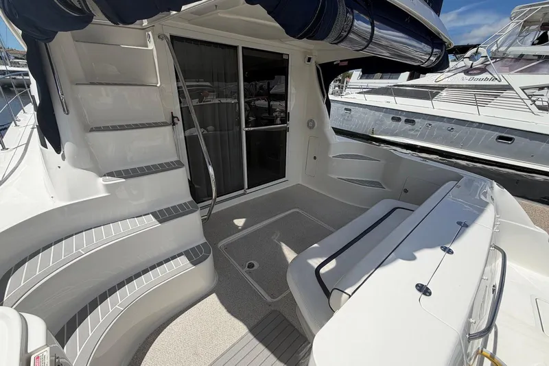 Slide: The Image of 2006 Sea Ray 44 Sedan Bridge yacht deck with seating and stairs, docked at marina. - 26