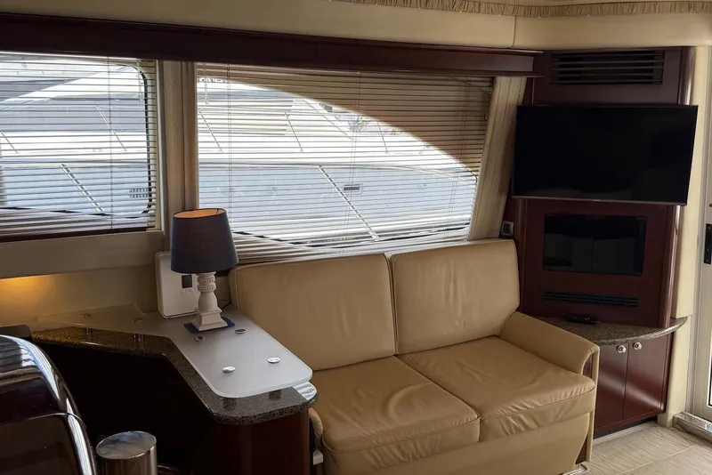 Slide: The Image of Interior of 2006 Sea Ray 44 Sedan Bridge with beige sofa, lamp, and mounted TV. - 30