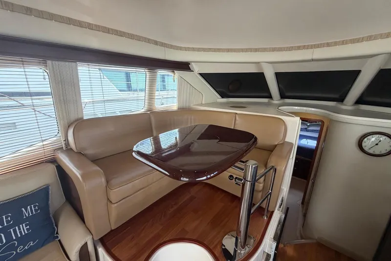Slide: The Image of Interior of 2006 Sea Ray 44 Sedan Bridge with leather seating and wooden table. - 32