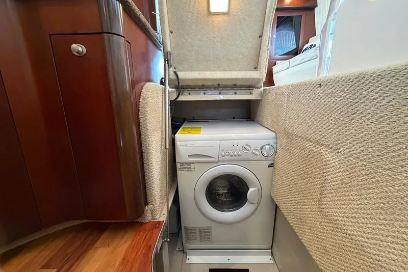 Slide: The Image of 2006 Sea Ray 44 Sedan Bridge interior with built-in washing machine under carpeted hatch. - 38