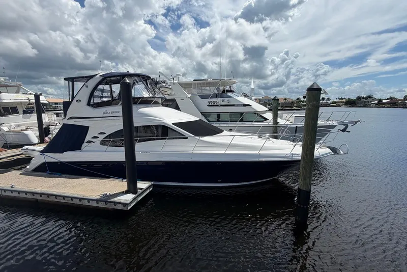 Slide: The Image of 2006 Sea Ray 44 Sedan Bridge yacht docked at marina under cloudy sky. - 4
