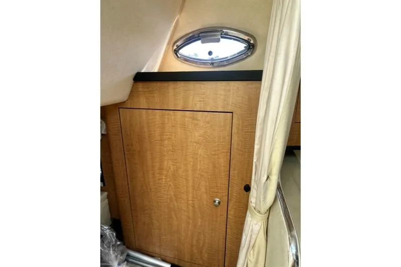Slide: The Image of Interior cabin of 2006 Sea Ray Sundancer 280 with wood paneling and porthole window. - 17