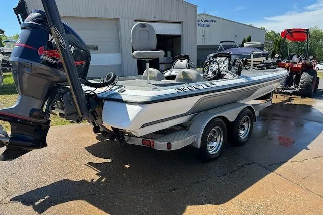 Slide: The Image of 2007 Skeeter ZX250 boat with Yamaha engine on trailer, parked outside a marine shop. - 7