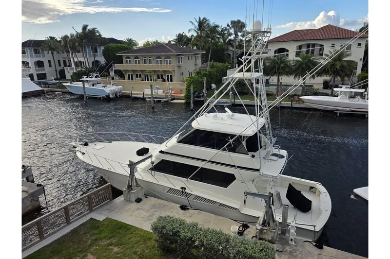 The Image of 1990 Hatteras 58 Convertible yacht docked by waterfront homes. - 0