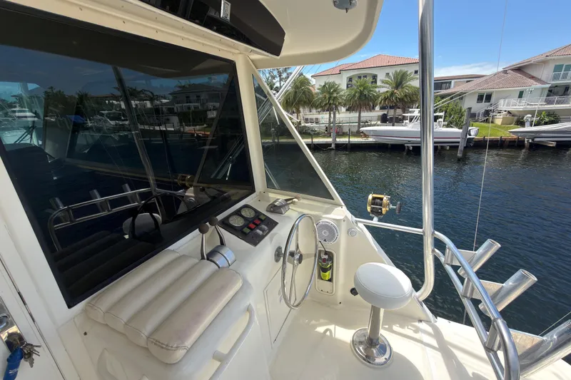 Slide: The Image of Cockpit view of 1990 Hatteras 58 Convertible yacht docked by waterfront homes. - 13