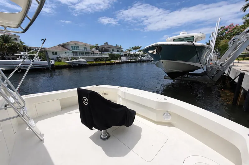 Slide: The Image of 1990 Hatteras 58 Convertible yacht docked in a scenic waterfront setting. - 14