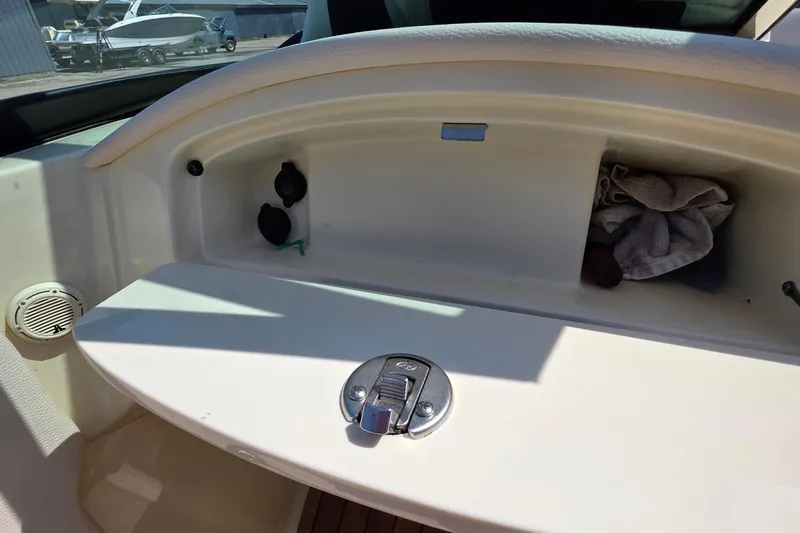 Slide: The Image of 2018 Chris-Craft Launch 23 boat storage compartment with latch and interior items. - 10