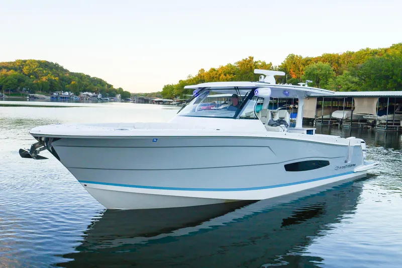 Slide: The Image of 2021 Regal 38 SAV boat on calm water, surrounded by lush greenery and docks. - 10