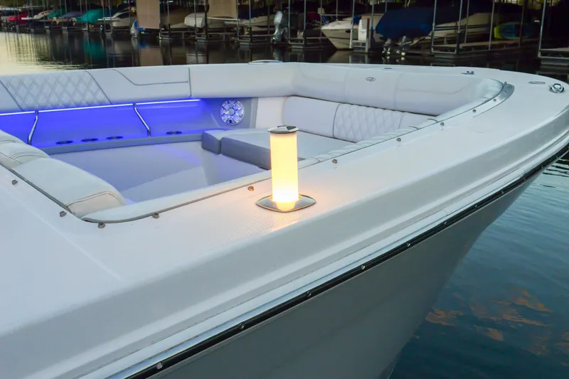 Slide: The Image of 2021 Regal 38 SAV boat with illuminated seating area and ambient lighting at a marina. - 19