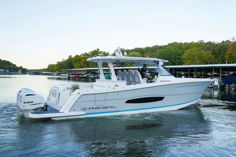 Slide: The Image of 2021 Regal 38 SAV boat cruising on a calm lake with Yamaha engines. - 2