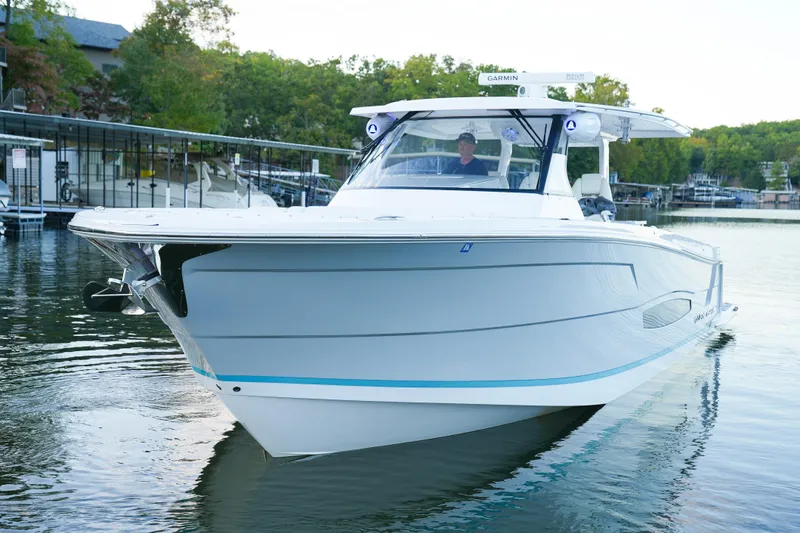 Slide: The Image of 2021 Regal 38 SAV boat on calm water, surrounded by lush greenery. - 28