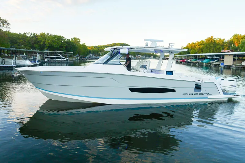 Slide: The Image of 2021 Regal 38 SAV boat on a calm lake with surrounding docks and trees. - 9