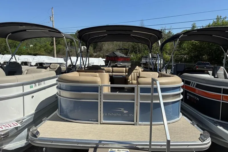 The Image of 2016 Bennington 22 SSRX pontoon boat with beige seating and canopy, docked outdoors. - 1