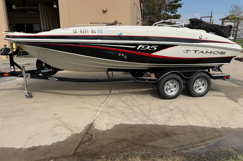 Slide: The Image of 2013 Tahoe 195 I/O boat on trailer, parked outdoors, showcasing sleek design and dual-axle wheels. - 3