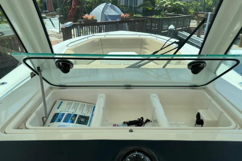 Slide: The Image of 2019 Sailfish 360 CC boat dashboard with open storage compartment and glass lid. - 25