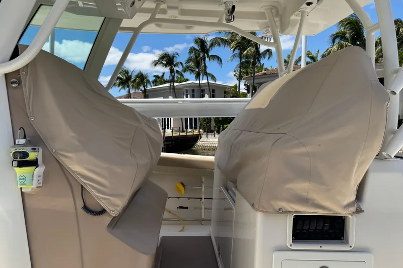 Slide: The Image of 2019 Sailfish 360 CC boat interior with covered seats and palm trees in the background. - 44