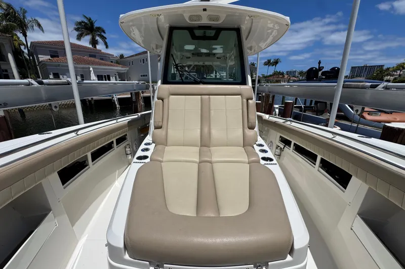 Slide: The Image of 2019 Sailfish 360 CC boat interior with beige seating, docked near waterfront homes. - 8