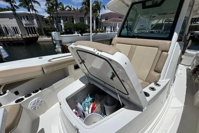 Slide: The Image of 2019 Sailfish 360 CC boat with open storage compartment, docked near waterfront homes. - 9