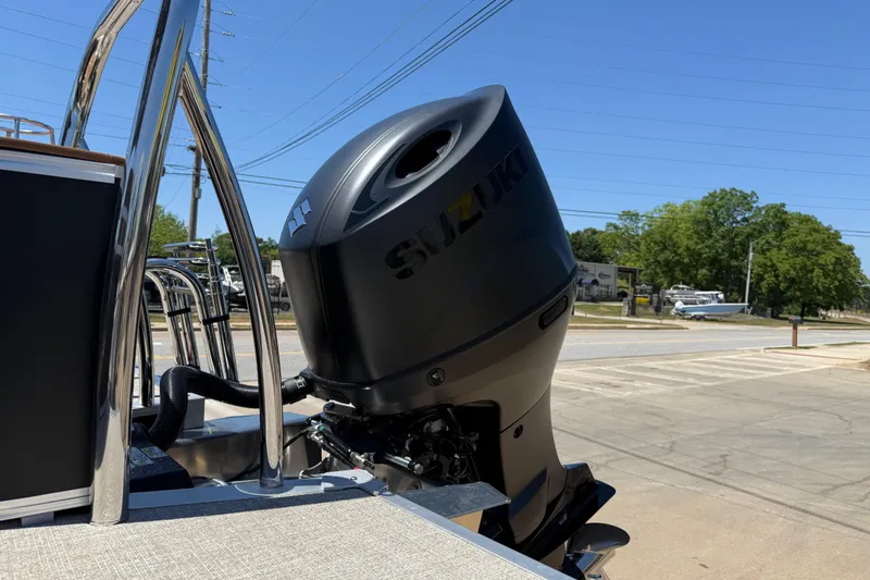 Slide: The Image of Outboard motor on 2026 Avalon VENTURE QUAD LOUNGE boat, parked outdoors under clear blue sky. - 8