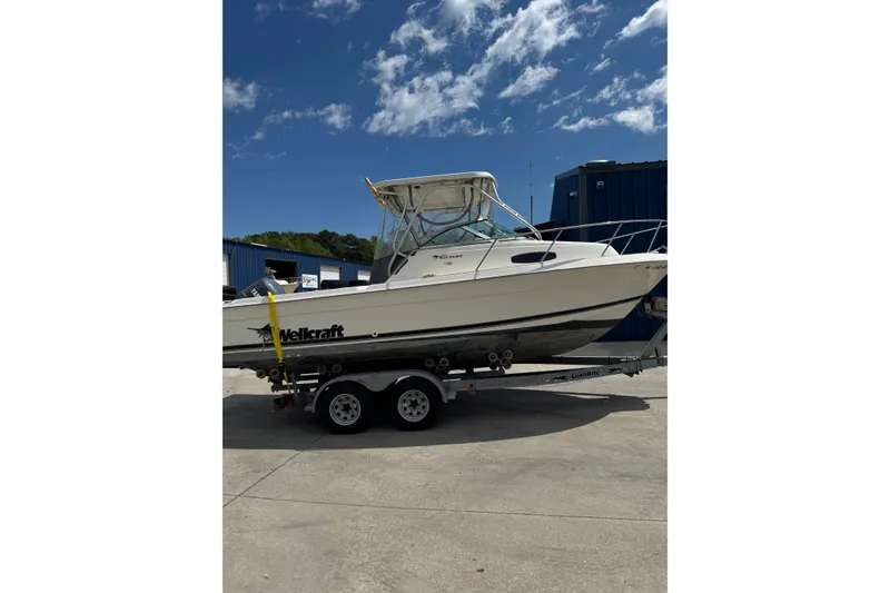 The Image of 2000 Wellcraft 22 Coastal Walkaround O/B boat on trailer under clear blue sky. - 1